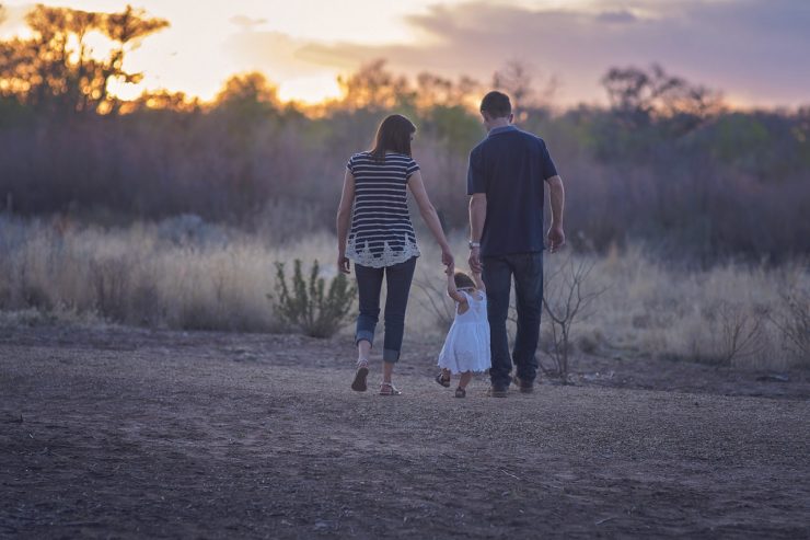 Young couple with toddler walking in the sunset