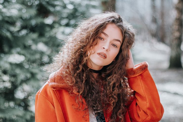 Woman with long curly hair wearing orange coat